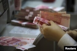 A clerk of ICBC bank counts Chinese one hundred Yuan at its branch in Beijing, China, April 13, 2016.