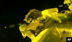 In this image made from video provided by NASA, U.S. astronauts Shane Kimbrough, left, and Peggy Whitson, install a shield on a relocated docking port outside of the International Space Station, March 30, 2017.