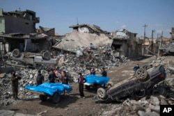 Residents carry the body of several people killed during fights between Iraq security forces and Islamic State on the western side of Mosul, Iraq, March 24, 2017.