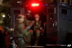 FILE - ATF agents board a truck to conduct an early-morning raid against members and associates of the MS-13 gang, May 17, 2017, in Los Angeles.