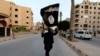 Seorang anggota yang loyal terhadap Negara Islam di Irak dan Syam (ISIS) mengibarkan bendera ISIL di Raqqa pada 29 Juni 2014. (Foto: Reuters)