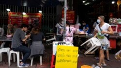 Adulwitch Tangsupmanee, 42, wearing a face mask to prevent the spread of the coronavirus disease (COVID-19), holds up a plastic chair for a customer at his late father's food stall in Bangkok's Chinatown, Thailand, October 6, 2021. (REUTERS/Athit Perawongmetha)