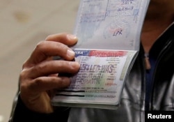 FILE - A Yemeni national who was denied entry into the U.S. earlier this because of the Trump administration's travel ban, shows the cancelled visa in his passport from his failed entry to reporters as he successfully arrives to be reunited with his family, at Washington Dulles International Airport in Chantilly, Virginia, Feb. 6, 2017.