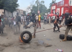 Police remove a burning tire as Haitians mount a nationwide strike to protest a growing wave of kidnappings, days after the abduction of a group of missionaries, in Port-au-Prince, Haiti, October 18, 2021.