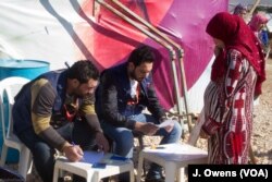 A Syrian women registers her details ahead of collecting items provided to help protect the refugees' makeshift shelters against the elements this winter.