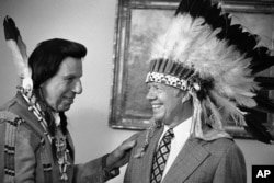 FILE - This photo shows Iron Eyes Cody, who fabricated Native American identity, presenting former President Jimmy Carter with a Native American headdress in the Oval Office in Washington on April 21, 1978. Cody, an Italian American, also gave Carter a Na