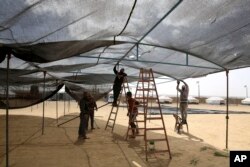 People set up a large tent in preparation for mass demonstrations along the Gaza strip border with Israel, east of Khan Younis, Thursday, March 29, 2018. (AP Photo/Adel Hana)
