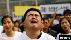 A family member of a passenger on board Malaysia Airlines MH370 cries as he shouts slogans during a protest in front of the Malaysian embassy in Beijing, March 25, 2014.