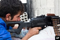 FILE - Young Kurdish People's Protection Units (YPG) fighter who recently volunteered holds a position with his weapon in Kobani, Syria.