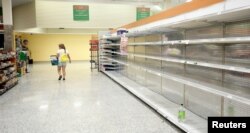 Seorang pengunjung berjalan melewati rak-rak yang kosong yang biasanya terisi oleh air minum di sebuah supermarket menjelang Badai Irma yang diperkirakan akan melanda Florida akhir pekan ini, 9 September 2017.