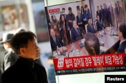 FILE - A man watches a TV broadcasting a news report on a high-level talks between the two Koreas at the truce village of Panmunjom, in Seoul, South Korea, Jan. 9, 2018.