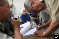FILE: Former U.S. President Jimmy Carter, center, observes the election process inside a polling station in the Sayeda Aisha neighborhood of Cairo, Egypt, Wednesday, May 23, 2012.