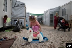 A Syrian child plays with a plastic toy horse at the refugee camp of Ritsona about 86 kilometers (53 miles) north of Athens.