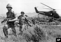 FILE - In this April 28, 1965 file photo, U.S. Marine infantry stream into a suspected Viet Cong village near Da Nang in Vietnam during the Vietnamese war. Filmmaker Ken Burns said he hopes his 10-part documentary about the War, which begins Sept. 17, 2017 on PBS, could serve as sort of a vaccine against some problems that took root during the conflict, such as a lack of civil discourse in America. (AP Photo/Eddie Adams, File)