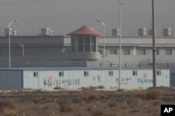 In this Monday, Dec. 3, 2018, photo, a guard tower and barbed wire fences are seen around a facility in the Kunshan Industrial Park in Artux in western China's Xinjiang region. (AP Photo/Ng Han Guan)