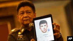 Police spokesman Lt. Gen. Prawuth Thavornsiri shows a photo of one of three men Thai authorities have issued new arrest warrants for in connection with the bombing case, in Bangkok, Thailand, Sept. 1, 2015.
