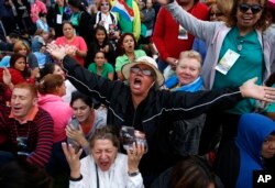 Inocencia Polanco, of Philadelphia and originally form the Dominican Republic, center in hat, joined by Freddy Espana of Honduras, left in striped shirt, and Maria Zuleta of Columbia, low center in white, pray a novena together as they wait for Pope Fran