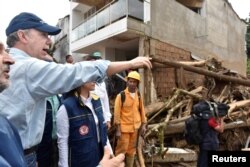 Colombia's President Juan Manuel Santos visits a flooded area after heavy rains caused several rivers to overflow, pushing sediment and rocks into buildings and roads in Mocoa, April 1, 2017.