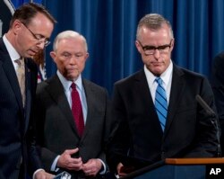 FILE - Andrew McCabe, right, accompanied by Attorney General Jeff Sessions, second from left, Deputy Attorney General Rod Rosenstein, takes the podium at a news conference at the Department of Justice, July 20, 2017, in Washington.