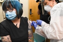 Nurse Kathe Olmstead, right, gives volunteer Melissa Harting, of Harpersville, N.Y. an injection as the world's biggest study of a possible COVID-19 vaccine, developed by the National Institutes of Health and Moderna Inc., gets underway Monday, July 27,