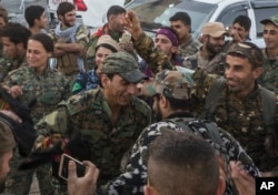 FILE - Members of the U.S.-backed Syrian Democratic Forces (SDF) dance a traditional Syrian 'Dabka" as they celebrate in front of stadium that was the site of Islamic State fighters' last stand in the city of Raqqa, Syria, Oct. 20, 2017.