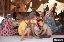 FILE - Iraqi Shiite Turkmen families fleeing the violence in the Iraqi city of Tal Afar, west of Mosul, arrive at Shangal, a town in Ninewa Province, June 17, 2014.