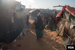 FILE - A girl carries a baby boy in a camp in Kismayo, Somalia, that is home to both displaced Somalis and returned refugees on September 27, 2016. (J. Patinkin/VOA)