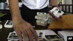 In this photo taken on Aug. 20, 2012, Director of Documentation Center of Cambodia, Youk Chhang arranges photos, a part of about a thousand of newly-discovered photo collection of detainees at the former Khmer Rouge main prison S-21, in his office in Phnom Penh, Cambodia.