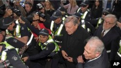 Cardinal George Pell, center right, is surrounded by police as he arrives at the Melbourne Magistrates Court in Melbourne, Australia, July 26, 2017.