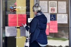 Seorang perempuan memperhatikan pengumuman lowongan pekerjaan di Arlington Heights, April 2020.