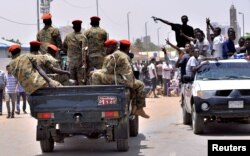 Sudanese demonstrators cheer as they drive towards a military vehicle, celebrating the ouster of President Omar al-Bashir, near the Defense Ministry in Khartoum, April 11, 2019.