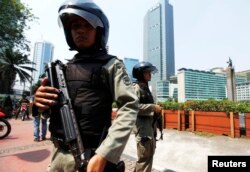 FILE - Indonesian anti-terror policemen hold their rifles as they stand guard at the business district in Jakarta.