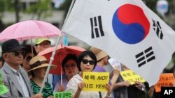 FILE - South Koreans hold signs and a national flag during a rally in support of the deployment of the advanced THAAD missile defense system, in Seoul, South Korea, July 18, 2016.