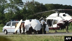 Police and military personnel use umbrellas to cover around a stretcher near a helicopter and an ambulance at a military airport in Chiang Rai on July 9, 2018, as rescue operations continue for those still trapped inside the cave in Khun Nam Nang Non Forest.