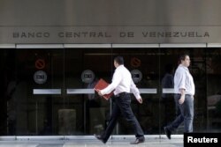FILE - People walk past an entrance of the Venezuela's Central Bank in Caracas, Venezuela, June 22, 2017.