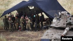 سربازان اسراییلی که در منطقۀ بلندی های گولان تحت تصرف اسراییل در کنار یک تانک جمع شده اند.