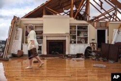 Jenny Bullard carries a pair of boots from her home that was damaged by a tornado, Jan. 22, 2017, in Adel, Georgia.