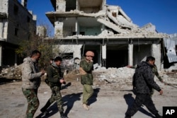 Russian and Syrian army soldiers gather at the last checkpoint before the front line with rebels, in Karam al-Tarab, east of Aleppo, Syria, Dec. 4, 2016.