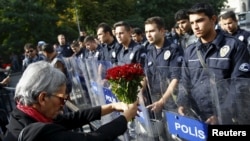 A demonstrator holds flowers before a police barricade during a commemoration for the victims of Saturday's bomb blasts in the Turkish capital, in Ankara, Turkey, Oct. 11, 2015.