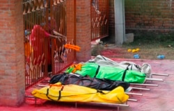Seorang anggota keluarga melempar karangan bunga untuk memberi penghormatan kepada kerabat yang meninggal karena COVID-19 di sebuah krematorium dekat kuil Pashupatinath di Kathmandu, Nepal. (Foto: AP)