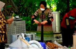 Menteri Sosial Tri Rismaharini ketika masih menjabat sebagai wali kota Surabaya saat menyediakan minuman dan makanan tambahan di dapur umum. (Foto: VOA/Petrus Riski)