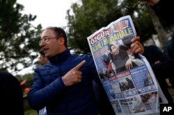 A man shows the front page of the daily Ozgur with a headline that reads " bloody intervention " as people gather outside the headquarters of Zaman newspaper in Istanbul, March 6, 2016.