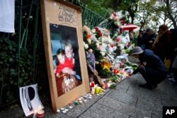 A woman lights candles to pay respect in front of the Bataclan concert hall in Paris, Nov. 13, 2016.