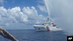 Chinese Coast Guard members approach Filipino fishermen as they confront each other off Scarborough Shoal in the South China Sea, also called the West Philippine Sea, Sept. 23, 2015.