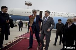 U.S. Secretary of State John Kerry (center L) shares a laugh with Kyrgyz Foreign Minister Erlan Abdyldaev upon his arrival at Manas International Airport in Bishkek, Oct. 31, 2015.