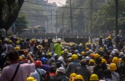 Pengunjuk rasa anti kudeta, di balik barikade darurat, berhadapan dengan aparat keamanan Myanmar di Yangon, Myanmar, Selasa 2 Maret 2021.