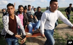 Palestinian protesters evacuate a wounded person during clashes with Israeli troops on the Israeli border with Gaza, east of Gaza City, March 16, 2018.
