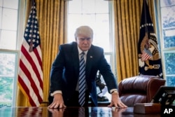 President Donald Trump poses for a portrait in the Oval Office in Washington, April 21, 2017.