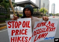 Protesters, mostly public transport drivers, display placards as they picket Petron Oil, the country's largest oil company, to protest the almost-weekly price increase of oil and other products and to demand its total rollback, June 5, 2018 in suburban Manila.