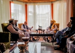 In this handout photograph released by the Taliban, former Afghan President Hamid Karzai, center left, senior Haqqani group leader Anas Haqqani, center right, Abdullah Abdullah, second right, head of Afghanistan's National Reconciliation Council.